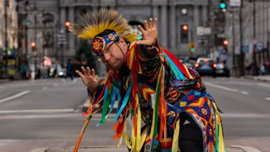 Person in traditional attire dancing on a city street.