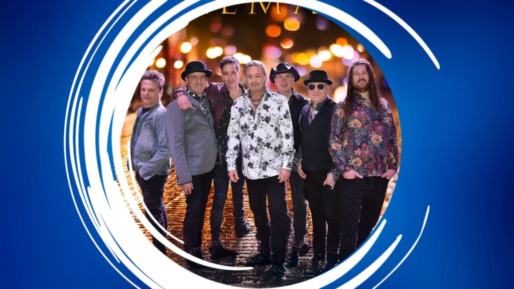 A group of seven men standing together on wet cobblestones, surrounded by abstract blue and white framing against a blurred nighttime cityscape.