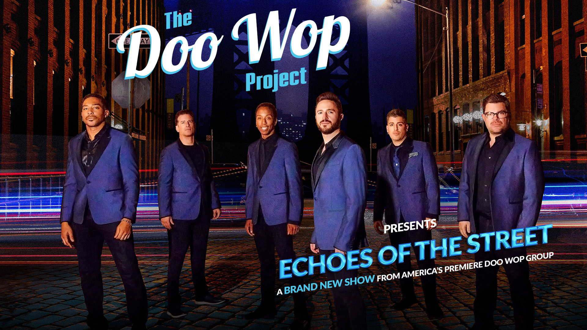 Six men in blue suits on a cobblestone street with streaks of light and surrounding buildings at night.