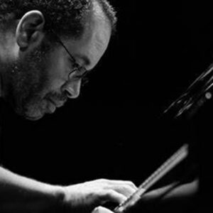 Man playing piano, focused and intense, in black and white.