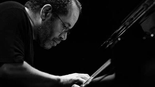 Man playing piano, focused and intense, in black and white.
