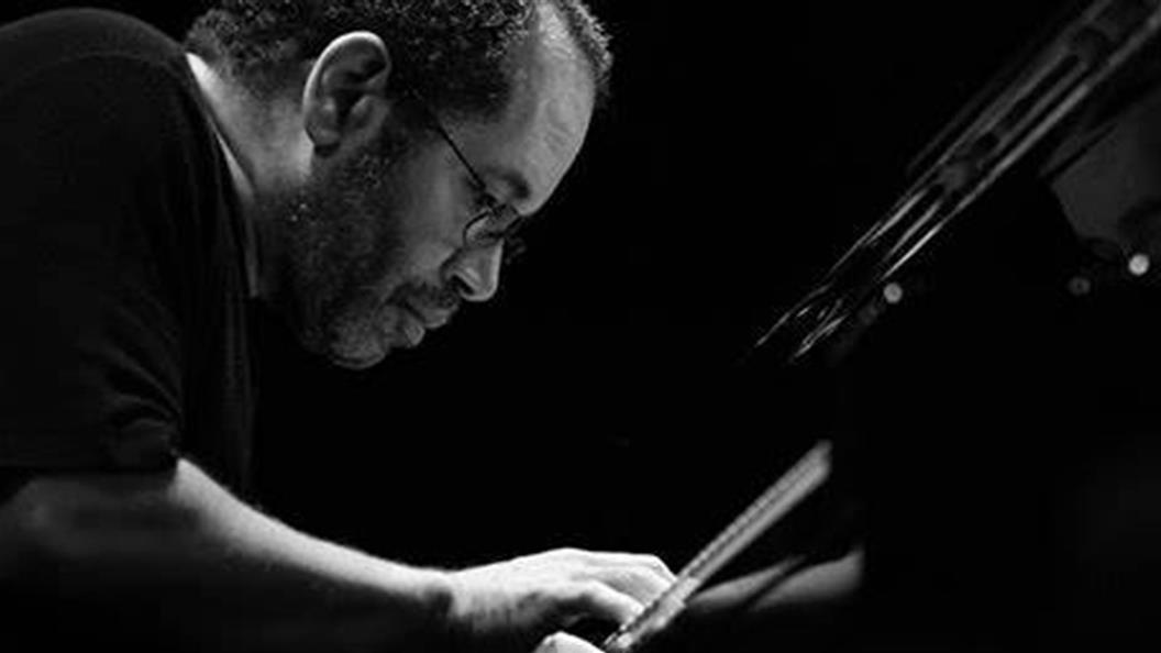 Man playing piano, focused and intense, in black and white.
