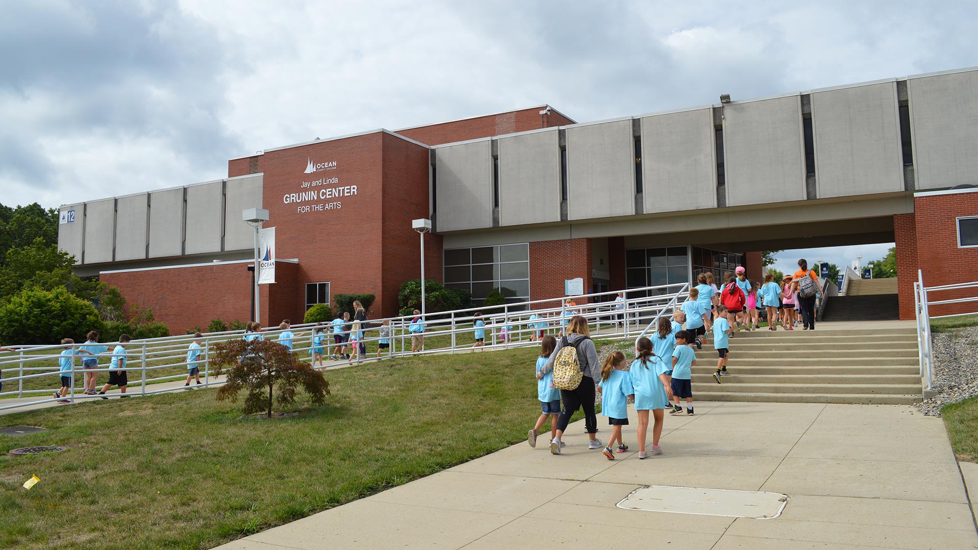 Children and adults walking toward the Jay and Linda Grunin Center for the Arts.