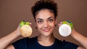 A person holding a gold and a silver Olympic medal.